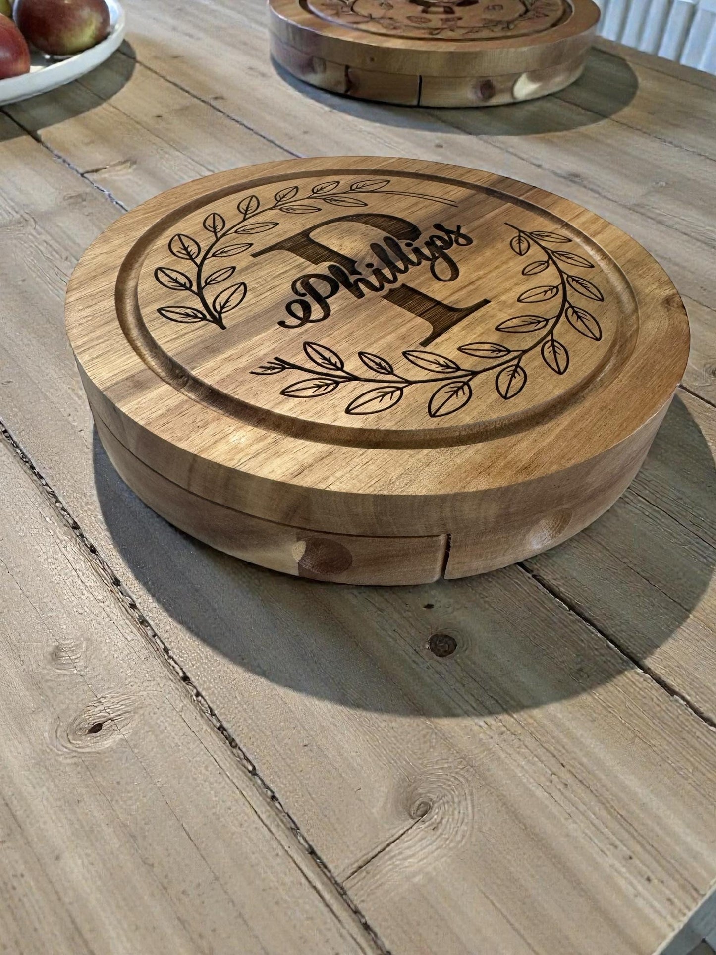“Side view of round acacia wood serving board with engraved design”